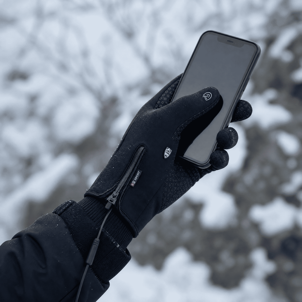 Gloved hand operating a smartphone in the snow